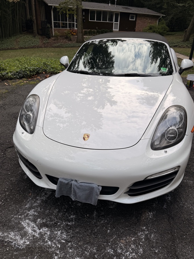 Glossy white Porsche Boxster hood reflecting the trees